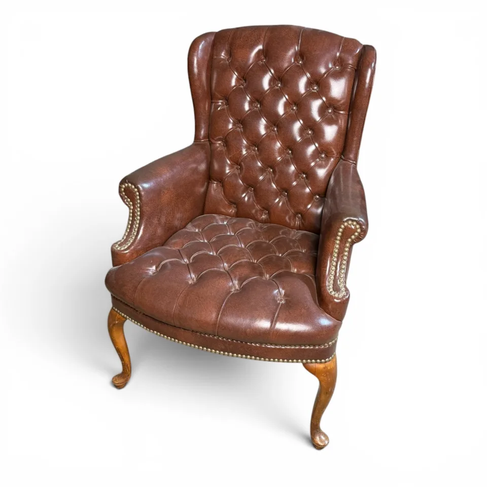 Para foteli uszakich (wing chairs) pikowanych guzikami typu chesterfield, skóra brązowa z ćwiekowaniem mosiężnym, nogi kabriolowe