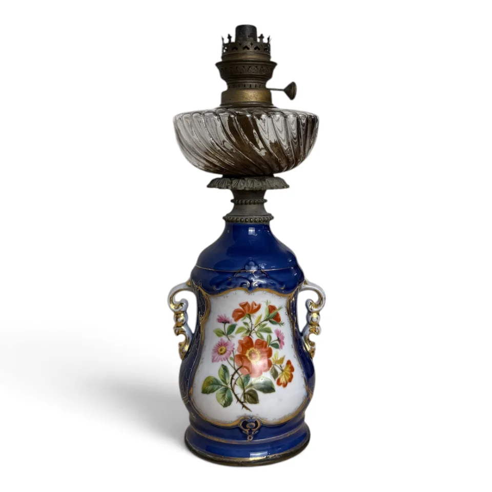 Lampa naftowa stołowa z porcelanową podstawą w kobaltowym kolorze, z malowanym bukietem kwiatów i szklanym zbiornikiem.