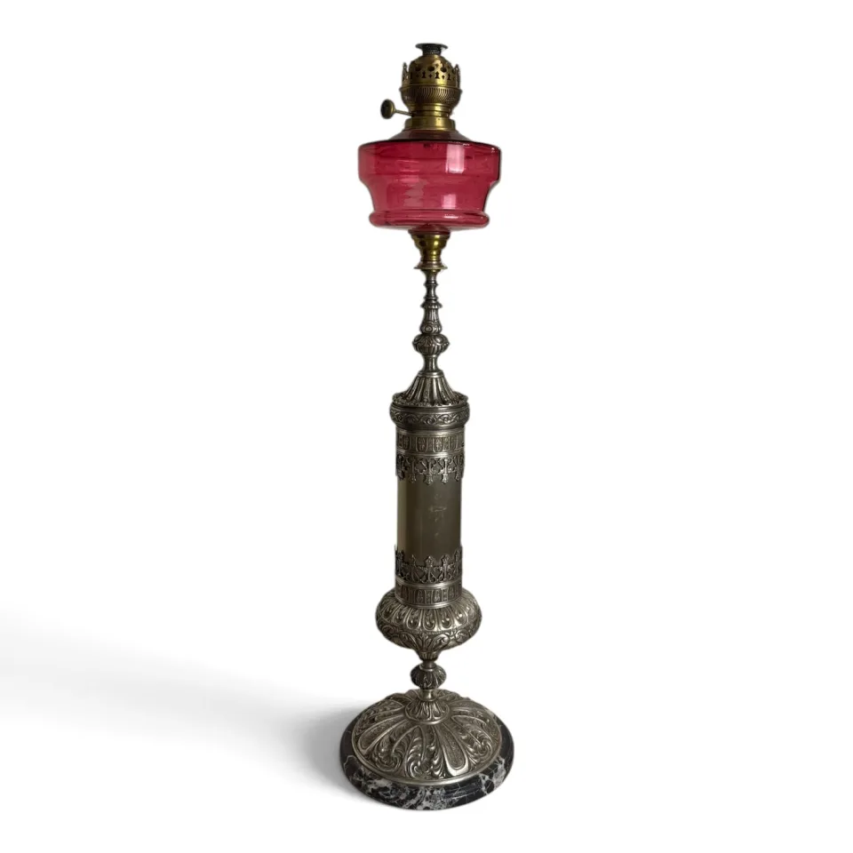 Lampa naftowa stołowa z rubinowym szklanym zbiornikiem i trzonem z metalu w kolorze srebra, na podstawie z czarnego kamienia, w stylu neorenesansowym.